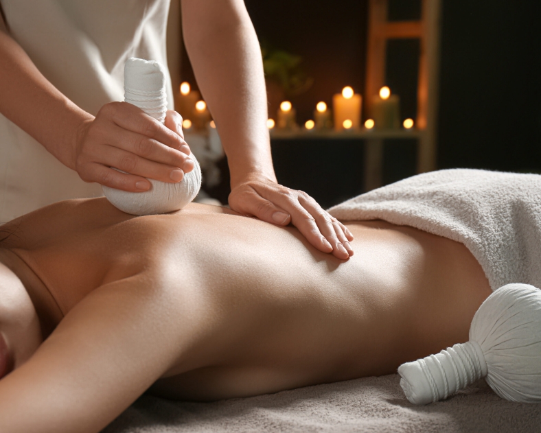 Young woman receiving herbal bag massage in spa salon, closeup